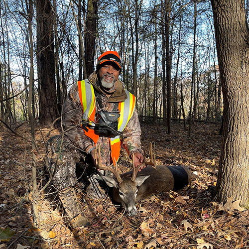 Johnny Center kneeling behind dead deer