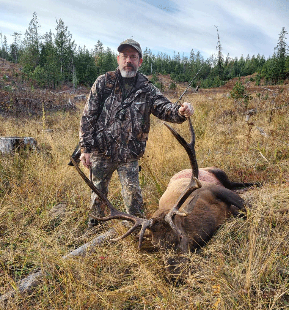 a man in the field with a downed elk