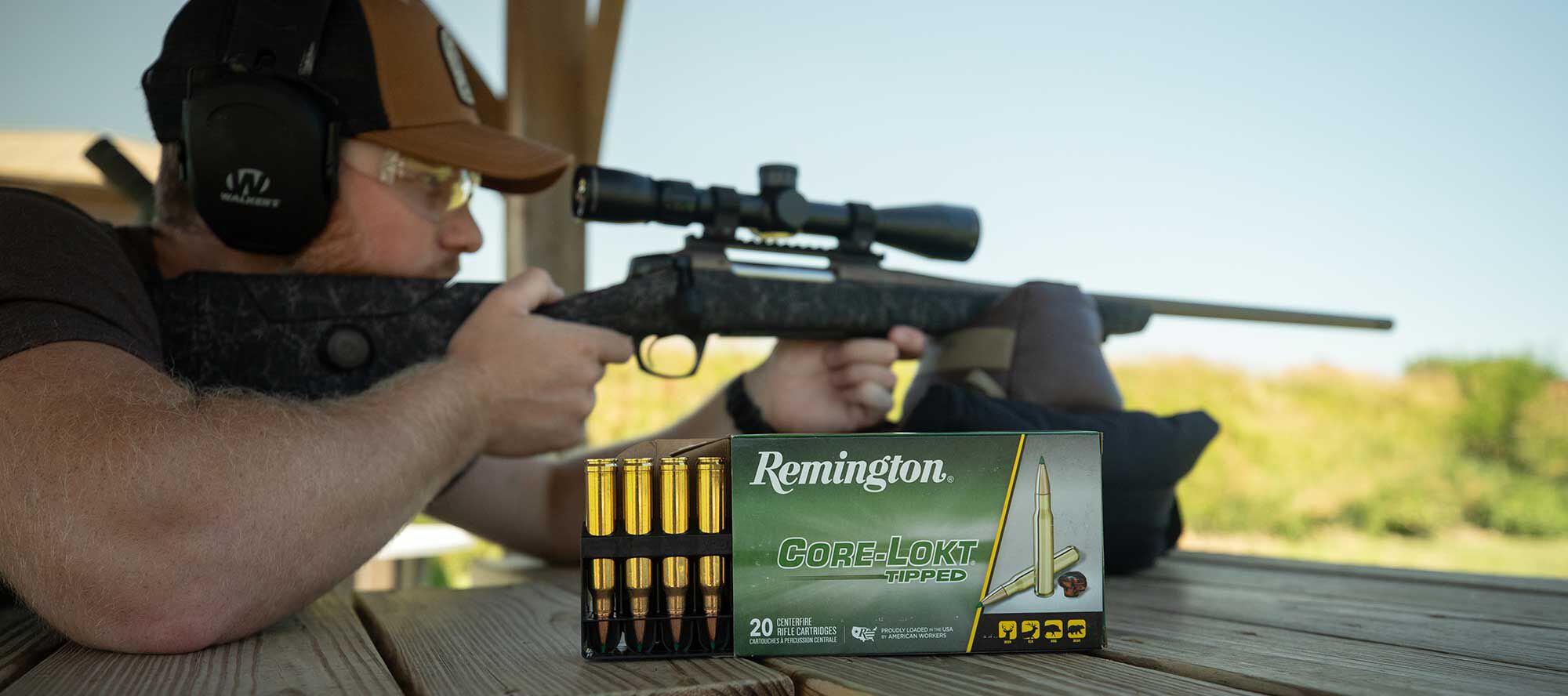shooter aiming rifle with a box of Core-Lokt Tipped 